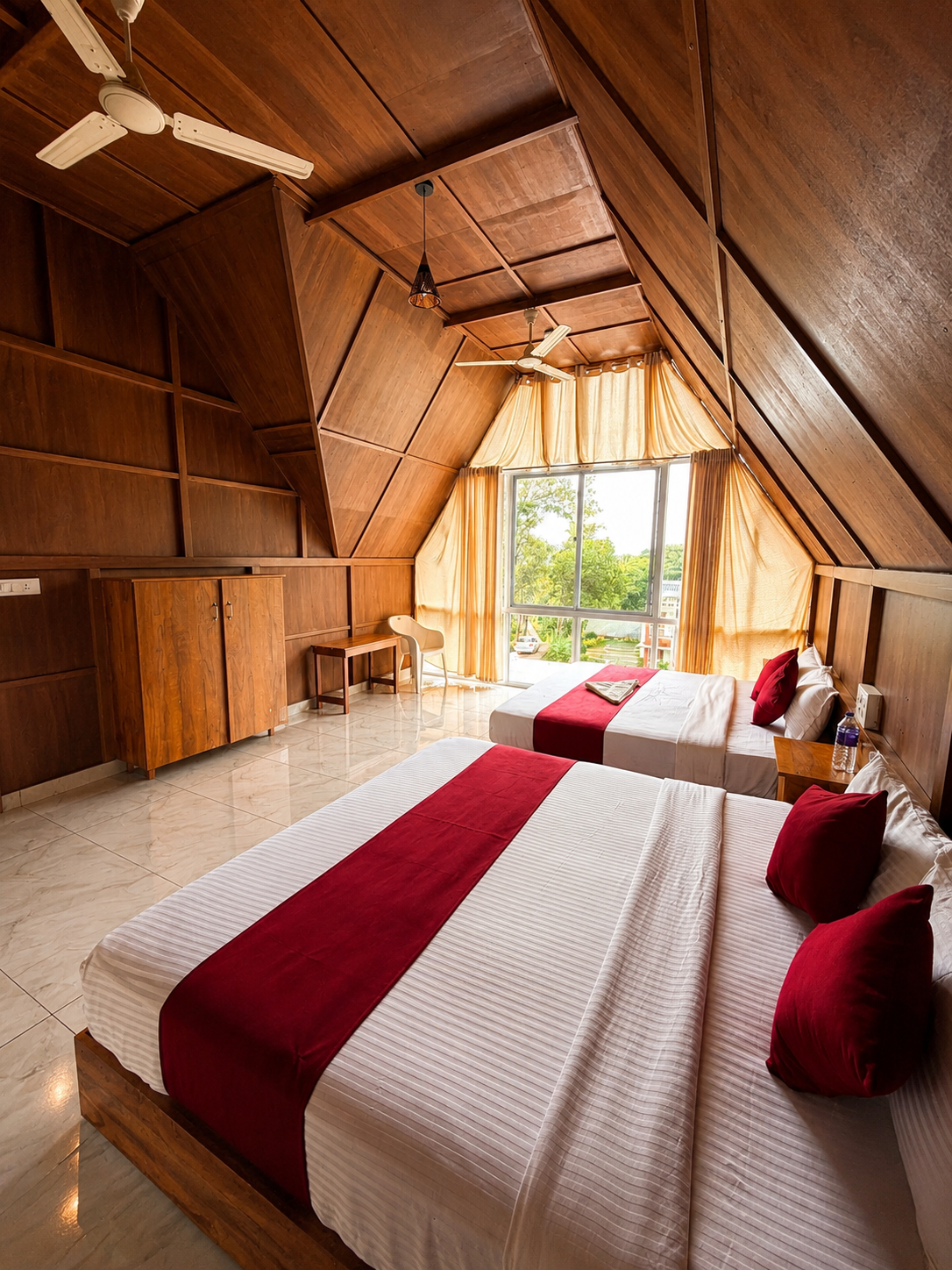 A-frame bedroom with two beds beneath a triangular valley window
