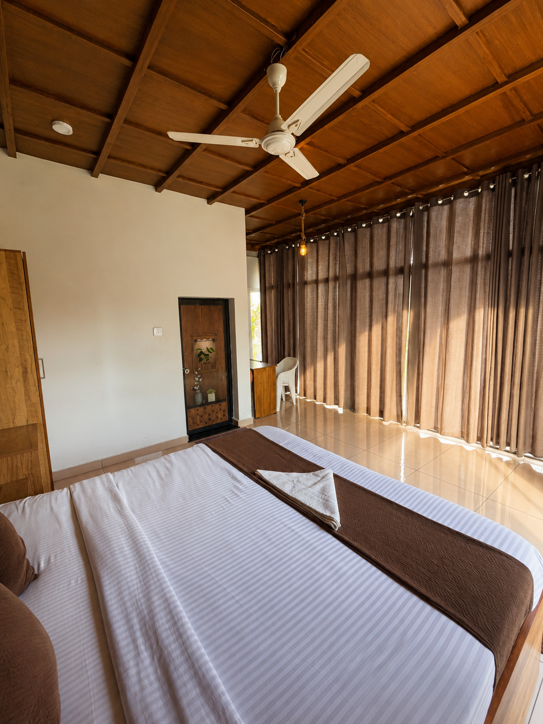 King bed beside a full wall of curtained glass
